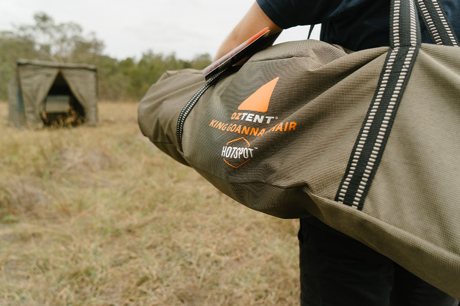 A King Goanna Chair bag over someone's shoulder with a tent in the background. 