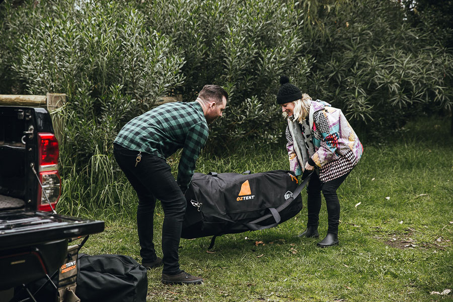 Two campers hoisting an Oztent gear bag. 