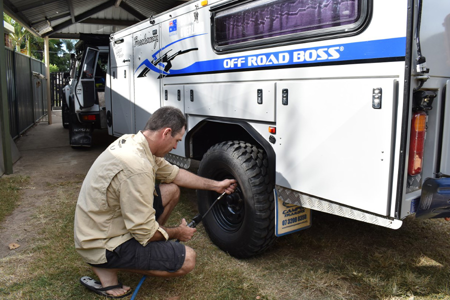 A man changing the tyre of a camper trailer. 