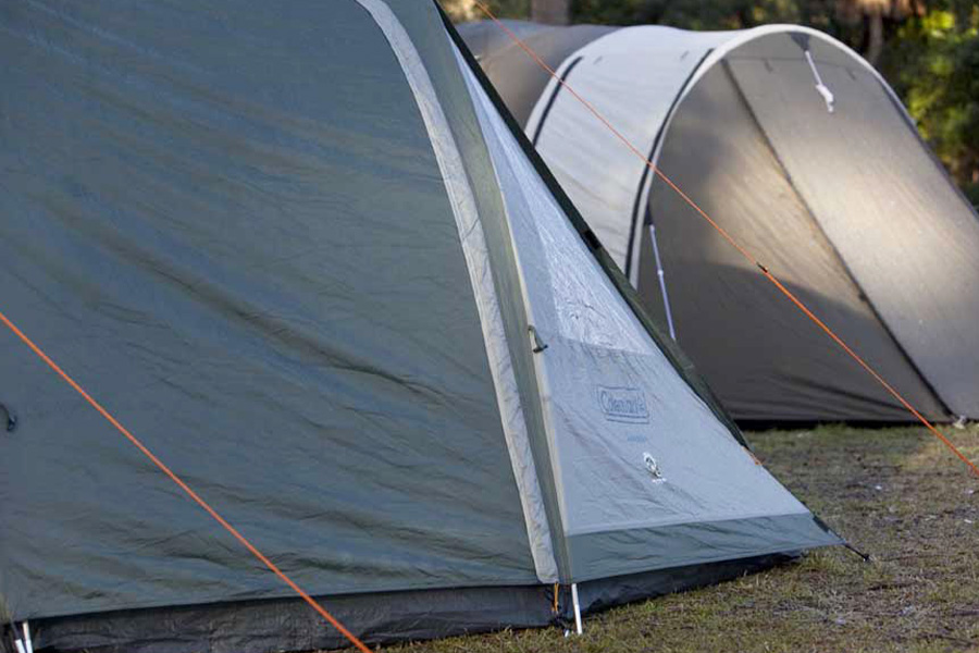Two tents side by side with guy ropes pegged out. 