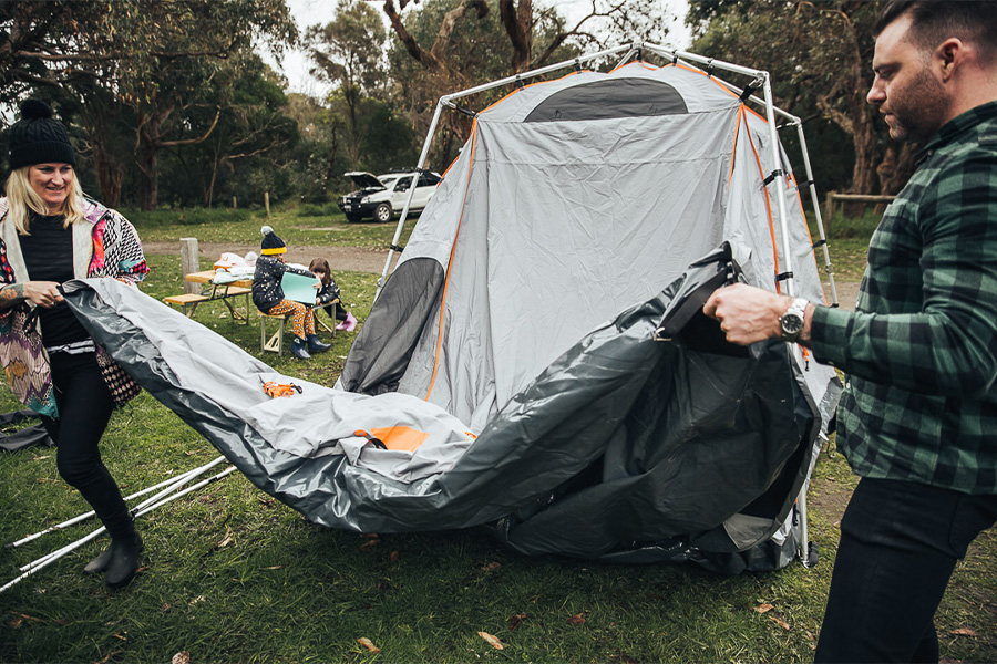 A family setting up a tent in the backyard. 