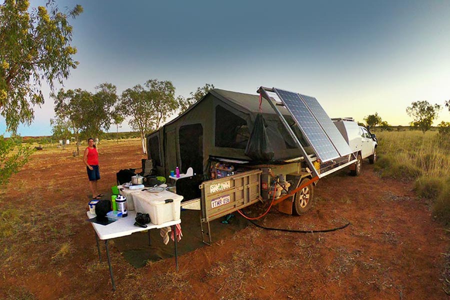 A camper trailer set up with solar panels in a remote location.