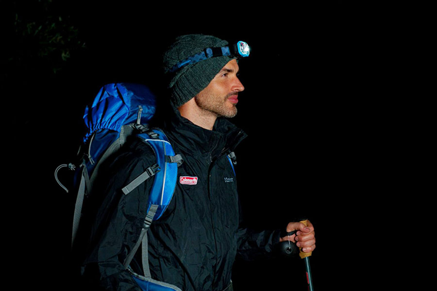 A man wearing a headlamp on a night hike