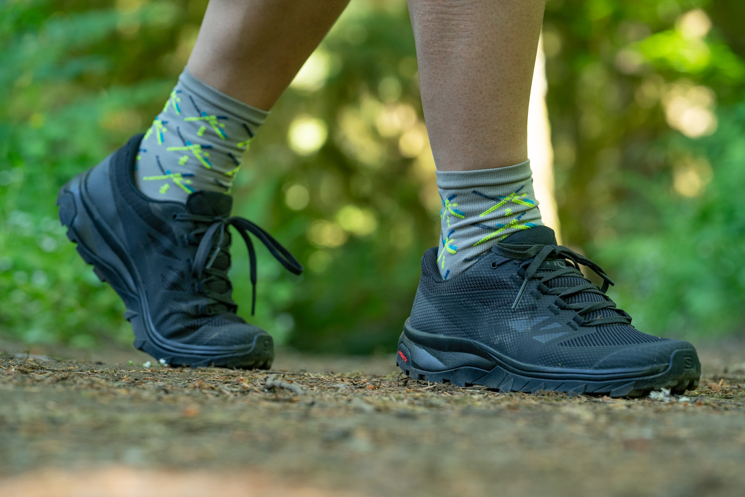 A close up of a hiker's black, low cut Salomon shoes