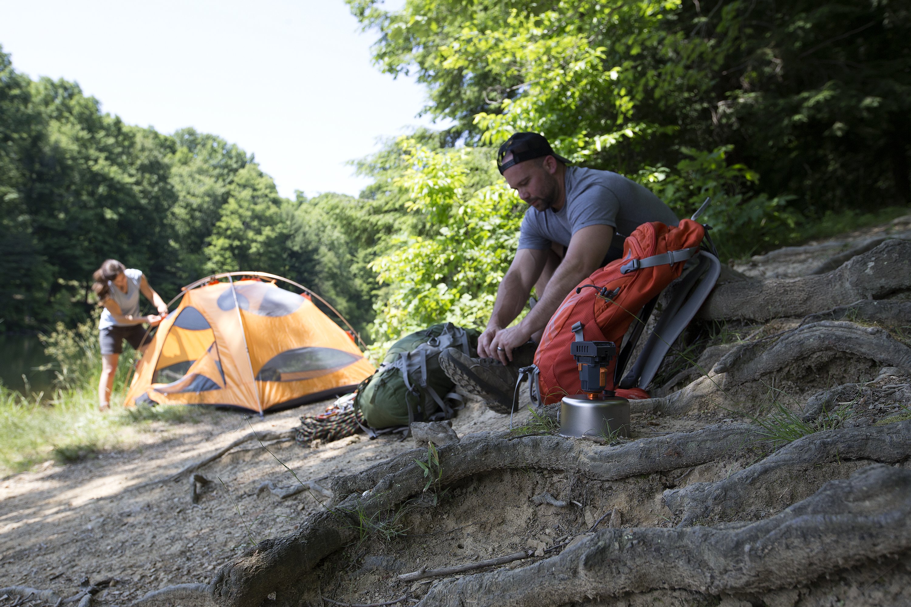 A man puts on his boots at a campsite