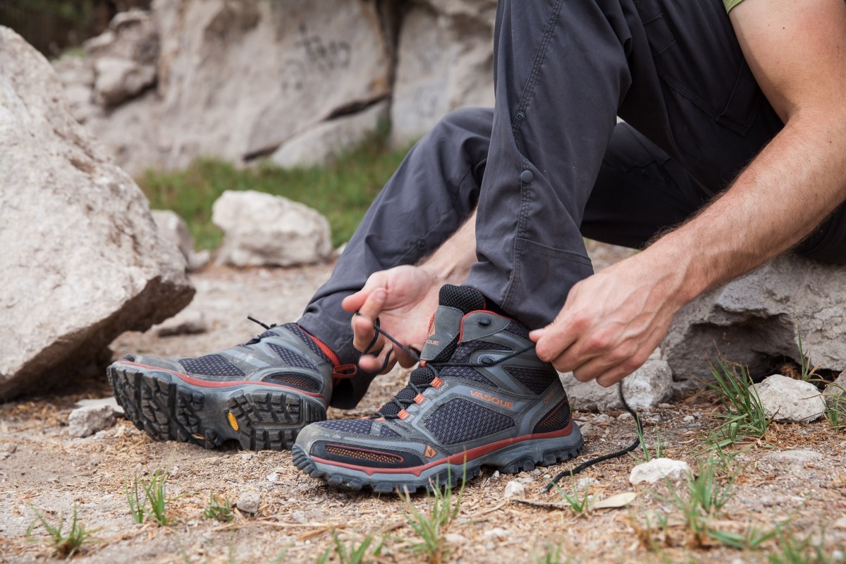 A close up of a hiker lacing up their Vasque high cut boots