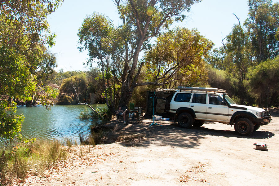 A 4WD pulled up to a beautiful blue water hole. 