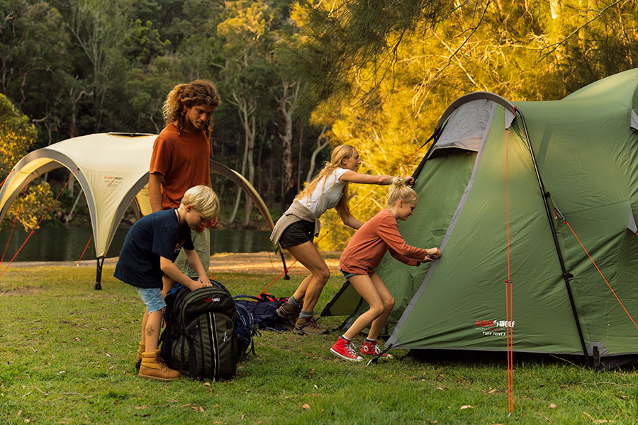 A young family unzipping a tent and packing a backpack. 