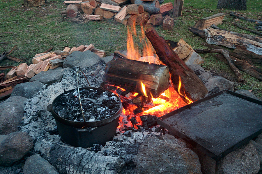 A camp oven nestled in a campfire.