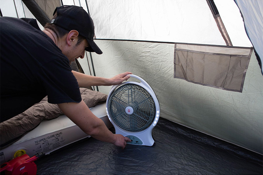 Man operating Coleman fan inside tent