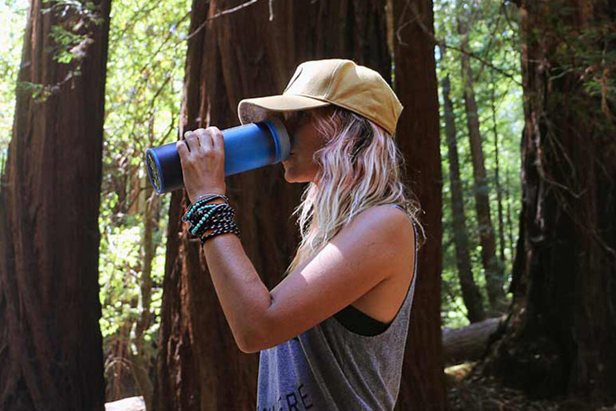 Woman drinking out of blue Grayl bottle