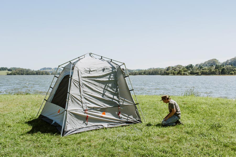 A tent without a fly is set up on grass near a river