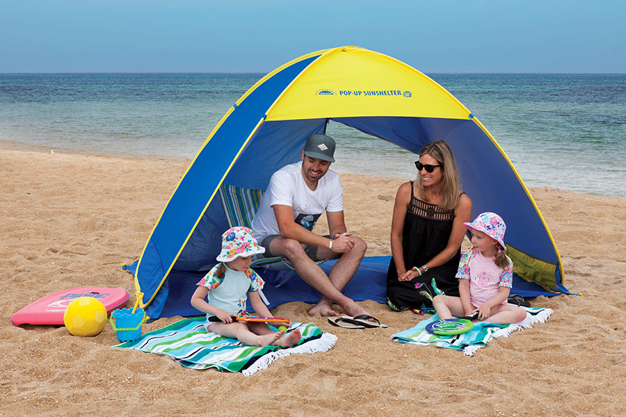 Family sitting under Smart Shade Pop Up Beach Shelter on the beach.