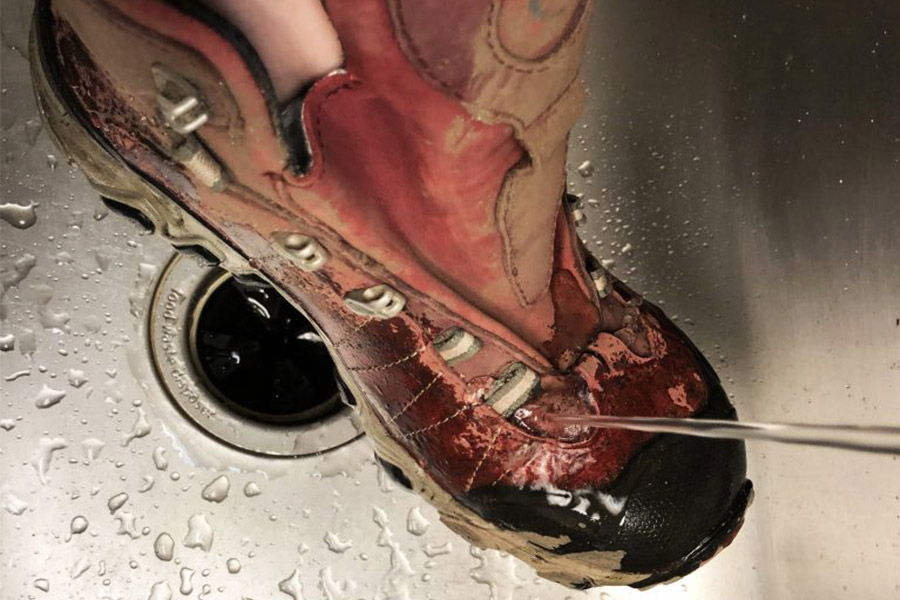 Washing boots under running tap