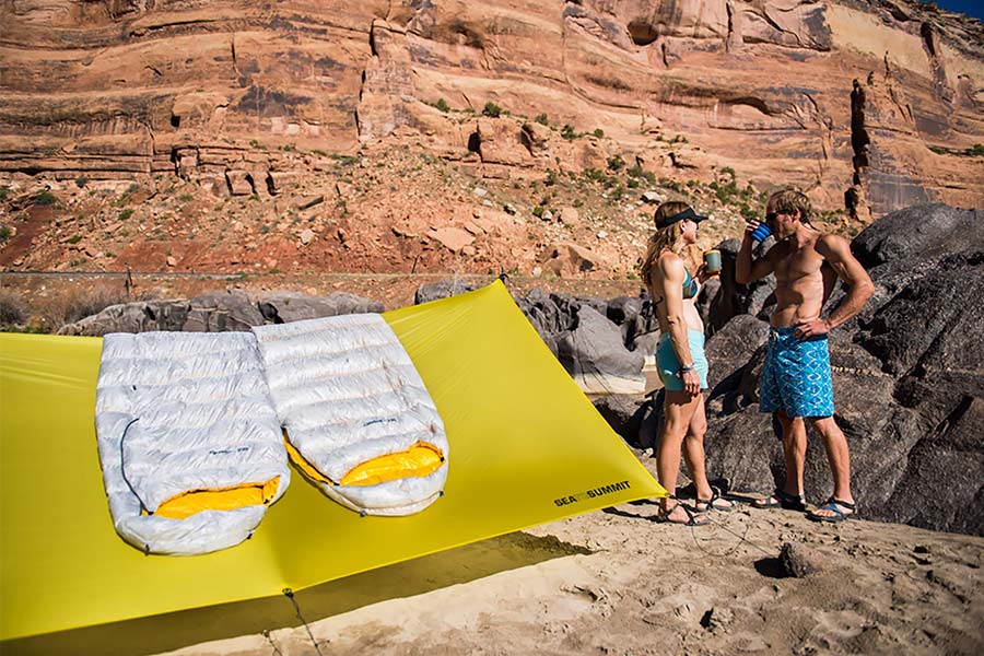 People drinking while Sea to Summit Spark sleeping bags lay over tent roof