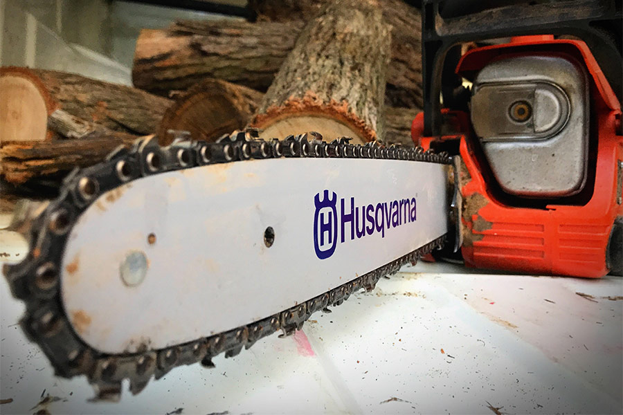 Husqvarna chainsaw next to logs of wood