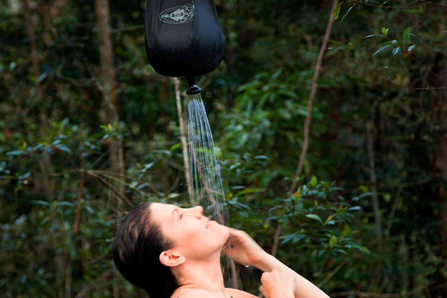 Woman showering in the outdoors underneath a pocket shower