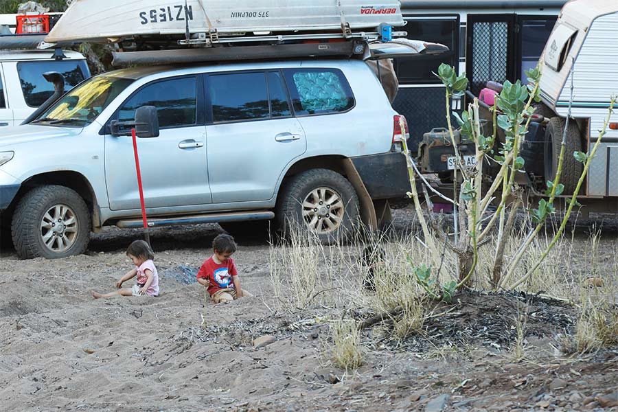 Kids playing in the dirt near a parked 4WD