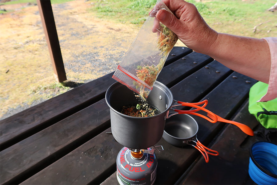 Pouring dehydrated food into a pot of boiling water to rehydrate