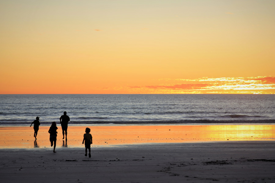 Family running on the beach at sunset