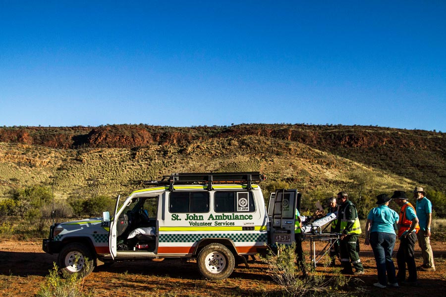 Person being wheeled into ambulance in the outback