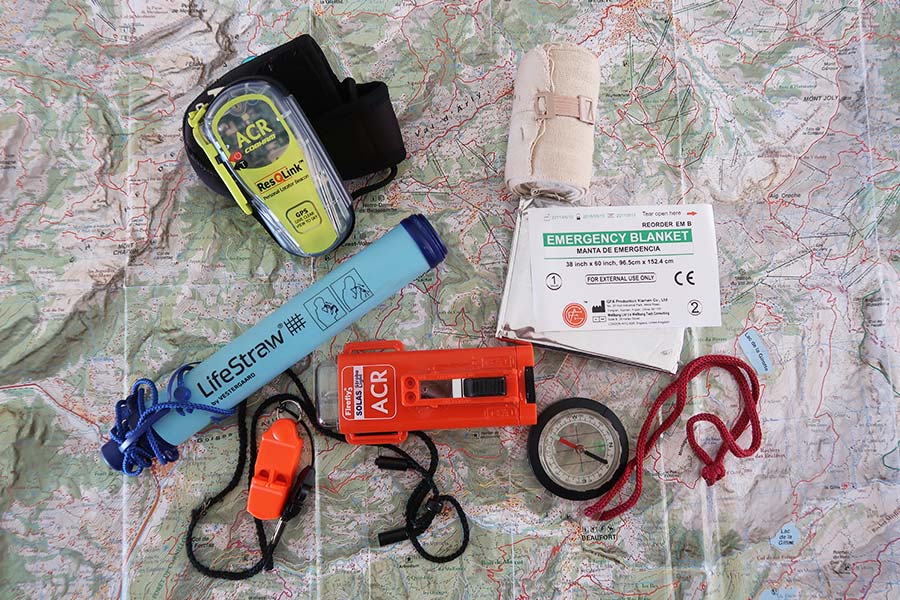 Bunch of hiking gear including LifeStraw, emergency blanket, ResQLink, etc.