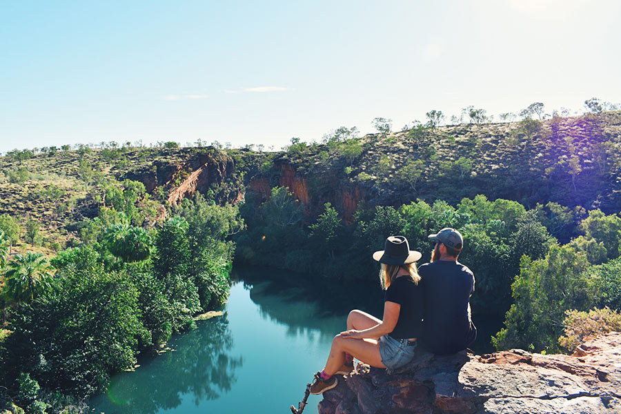 Couple looking out over a cliff at the greenery over a river