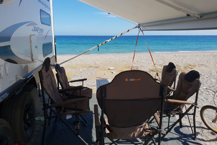 Oztent chairs setup outside caravan under awning on beach