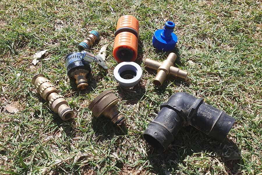A bunch of hose and water connections spread out on the grass