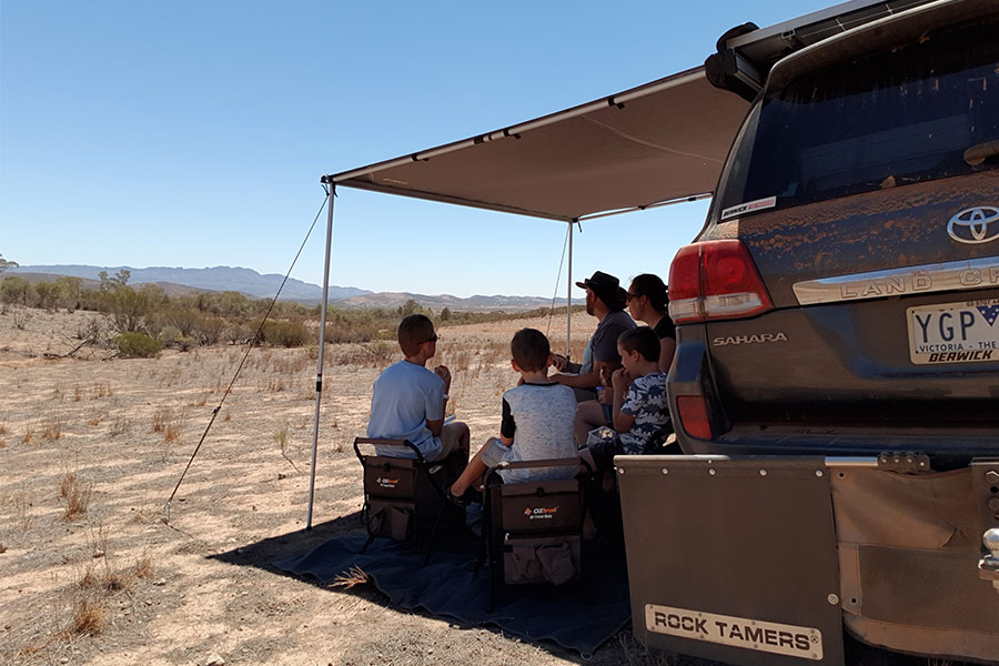 Family sitting outside at table under 4WD awning
