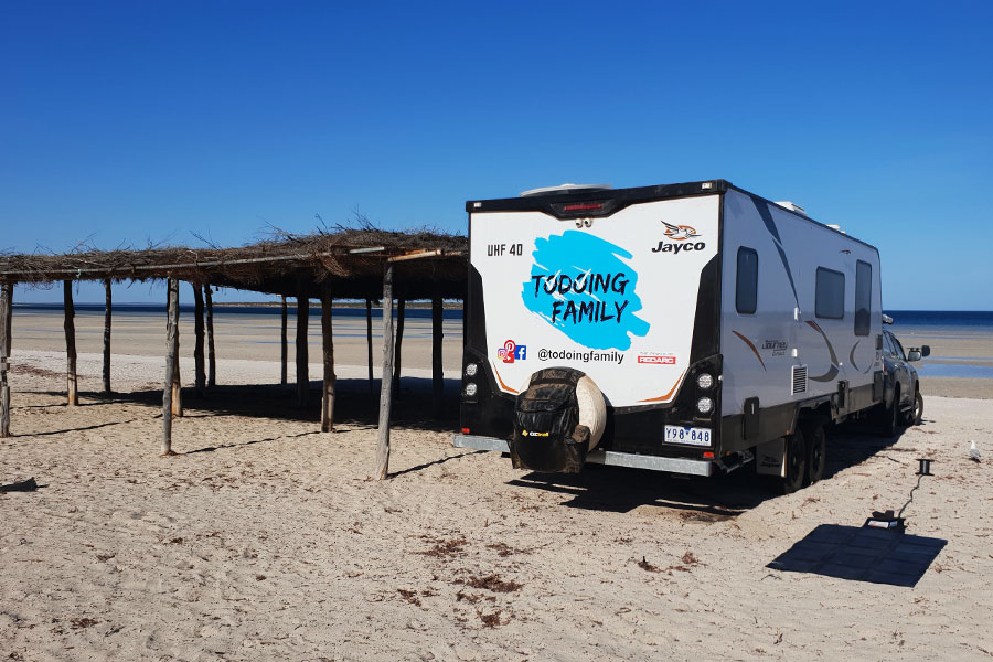 Caravan positioned next to a hut on the beach