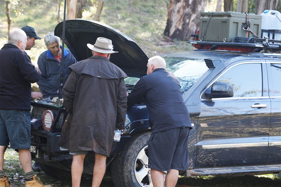 Men inspecting under a vehicle's bonnet