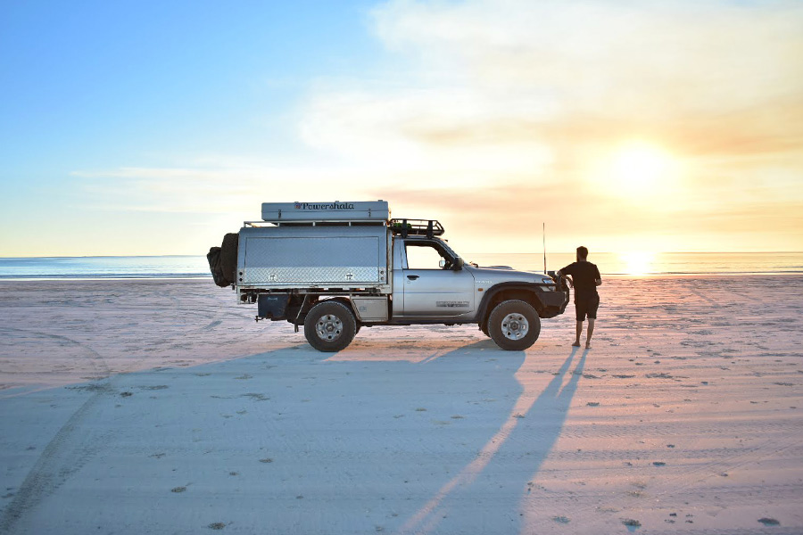Man standing next to vehicle on Cable Beach at sunset