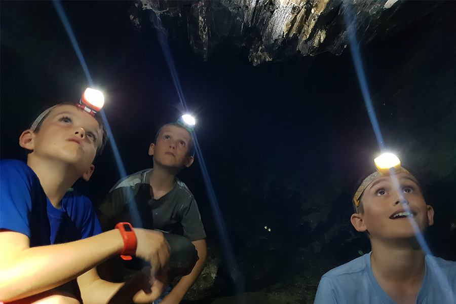 Three boys wearing head torches at night