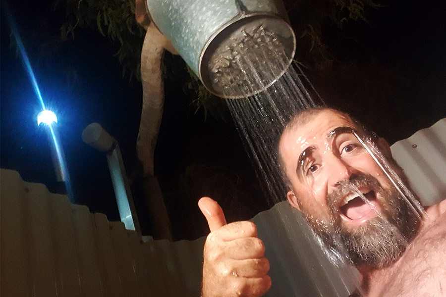 Man having shower with bucket of water with holes in it