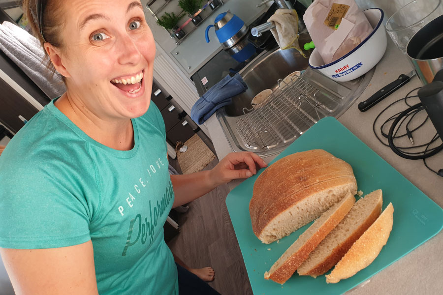 Woman cutting loaf on bread on a chopping block in her caravan