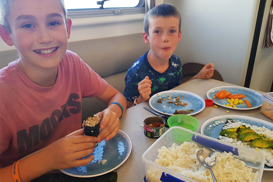 Two boys eating homemade sushi in a caravan