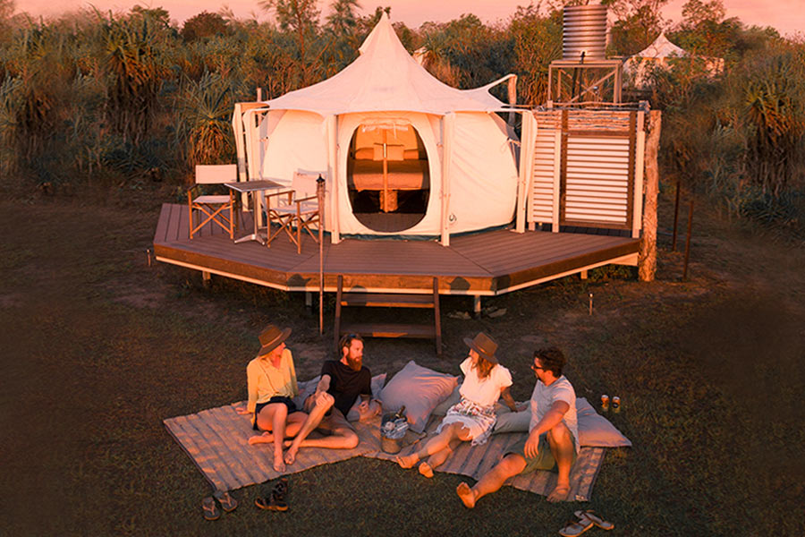 4 people relaxing outdoors near their tent at Top End Safari Camp, NT