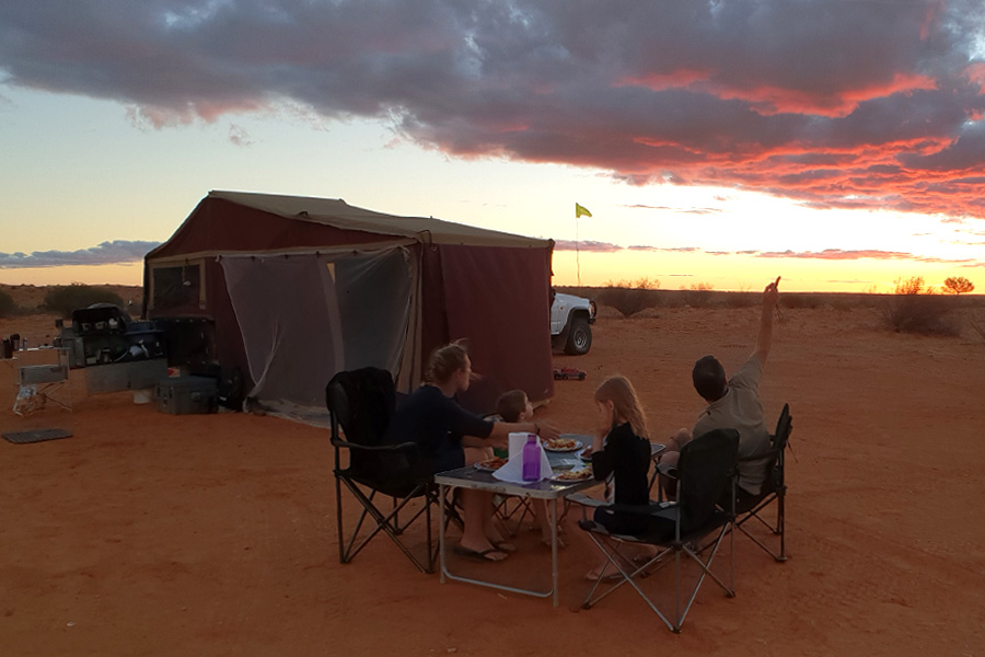 Family eating dinner at a table at sunset at their campsite 