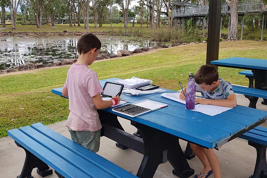 Two boys doing their school work on an outdoor picnic bench
