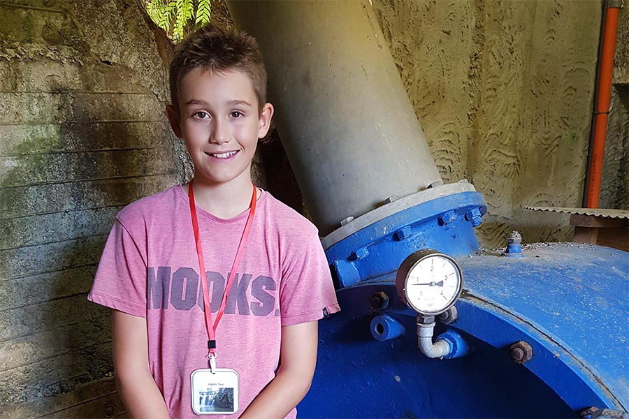 Boy posing for photo next to a piece of engineering equipment.