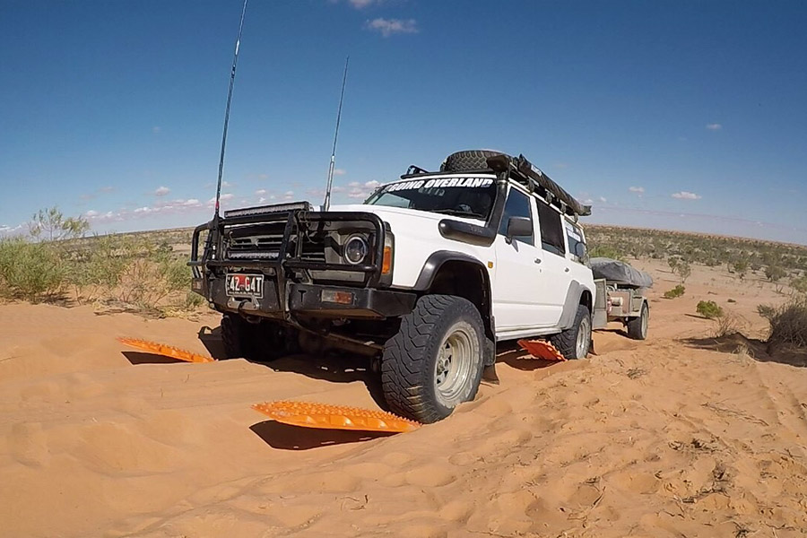 Vehicle using Maxtrax recovery boards to become unbogged from the sand.