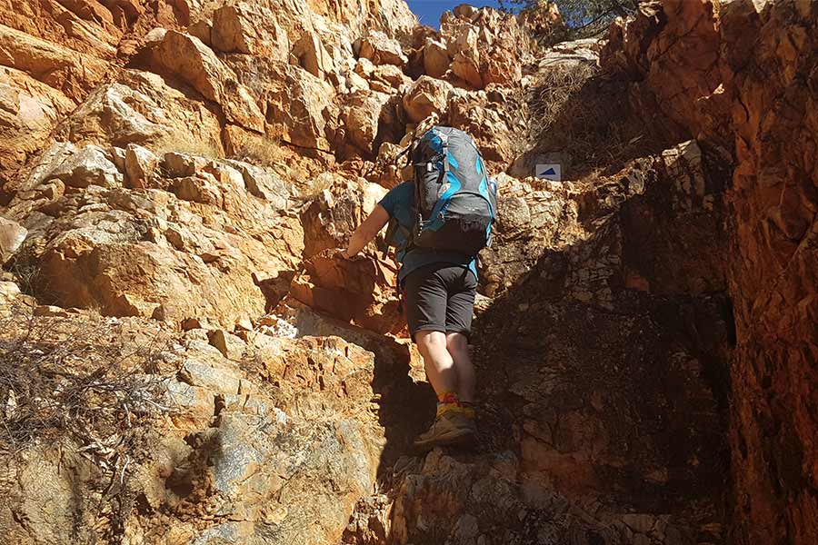 Climbing up a rocky cliff face along the Larapinta Trail