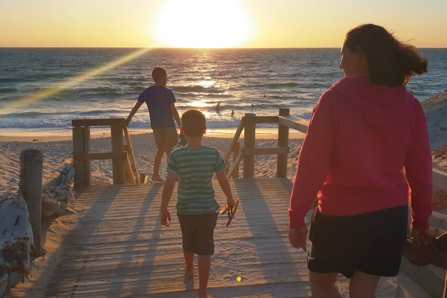Family walking towards view of sunset over West Beach in South Australia