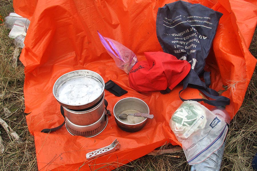 Lightweight hiking cooking gear resting on an orange tarp on the ground