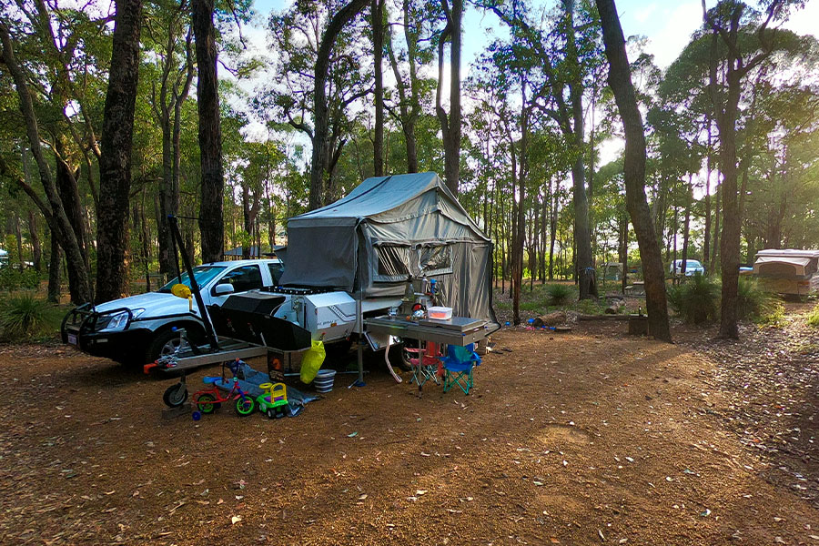 A camper trailer parked at campsite surrounded by toys. 