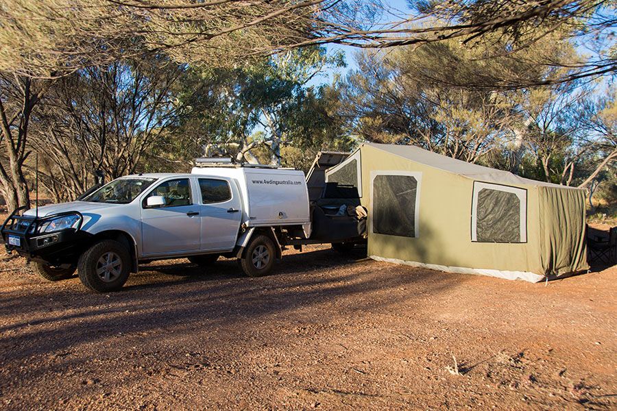 A 4WD with a camper trailer set up in the outback.