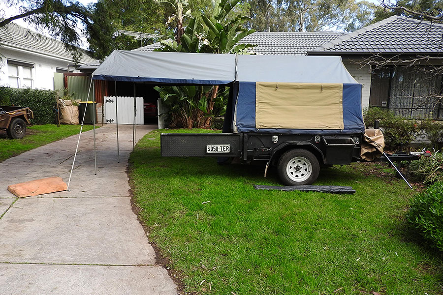 A camper trailer set up in a backyard. 
