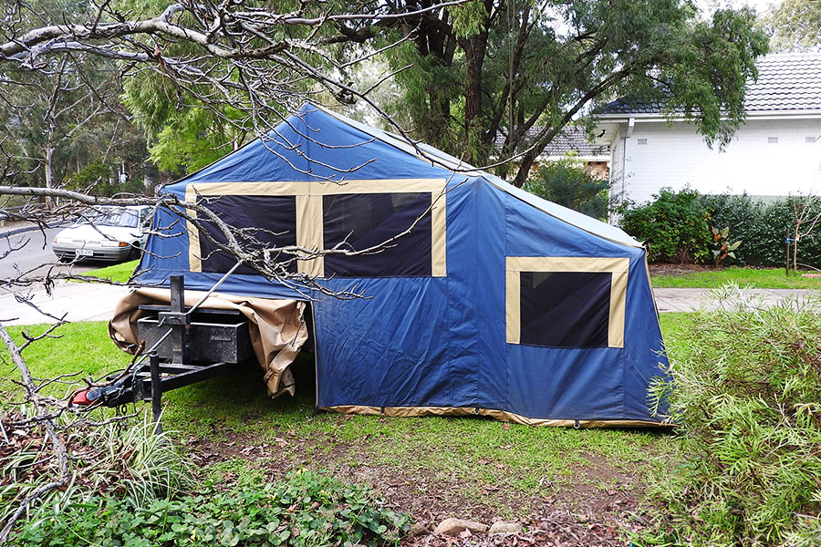 A camper trailer set up in a backyard. 