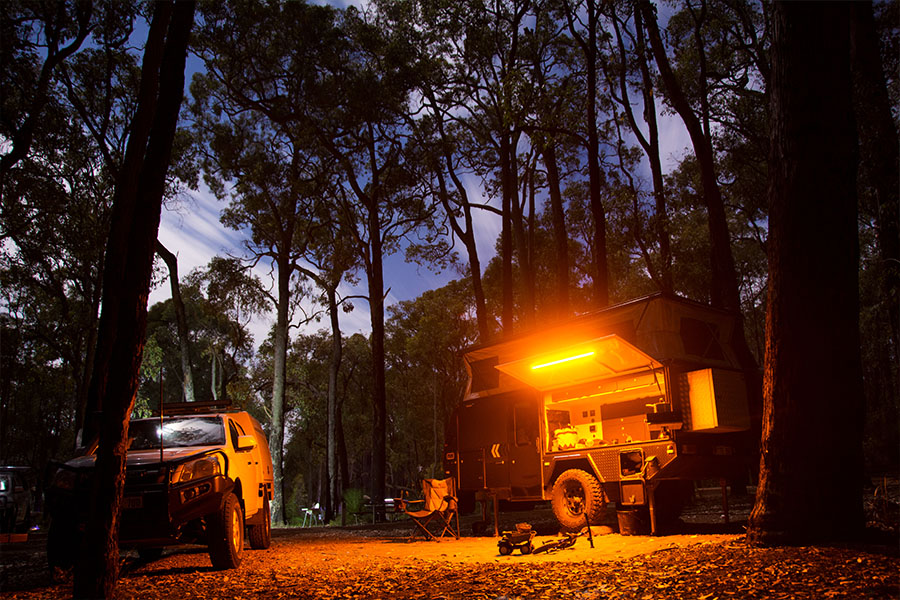 A camper trailer set up at night with amber lighting.